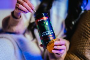 Woman taking a Red Vein kratom capsule from the jar.