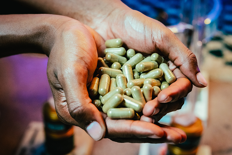 Woman holding Tri Sprout kratom capsule